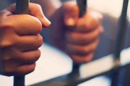 A person holding on to jail cell bars