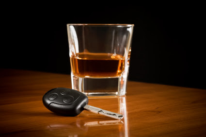 A glass of brown alcohol sitting next to a car key